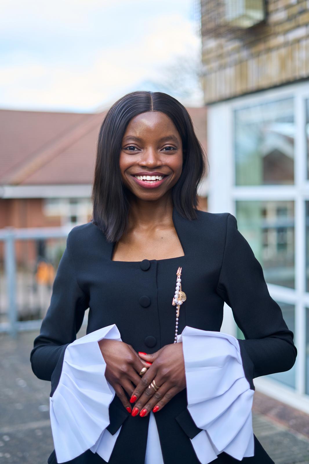Anave Alonge smiling outdoors in a black and white outfit